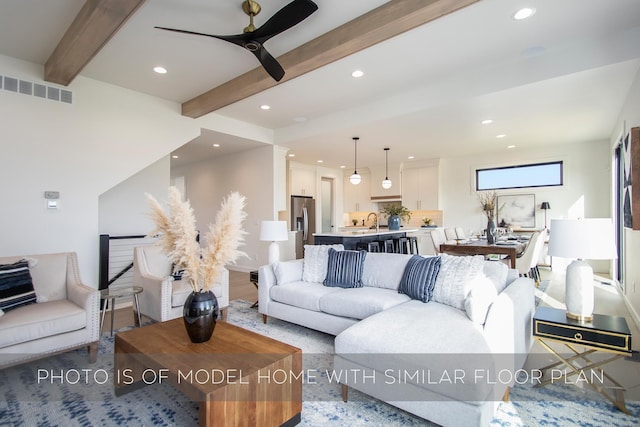 living room with beam ceiling, ceiling fan, and sink