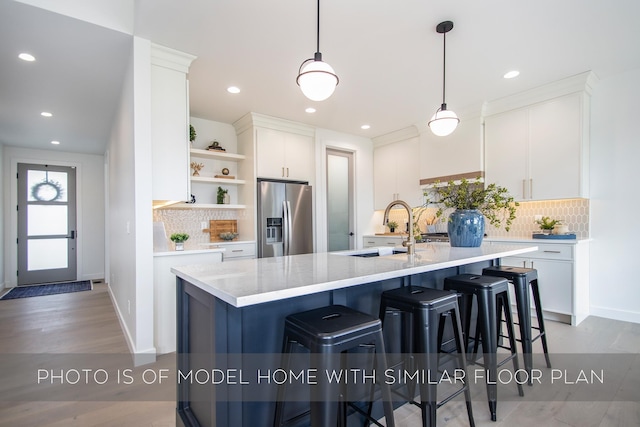 kitchen with decorative light fixtures, sink, white cabinetry, and stainless steel refrigerator with ice dispenser