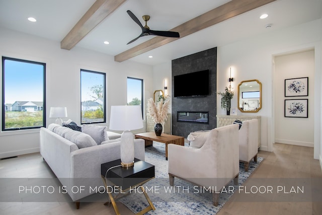 living room with ceiling fan, beam ceiling, and a premium fireplace