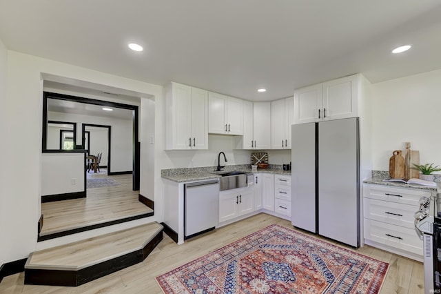 kitchen with white cabinetry, dishwashing machine, white refrigerator, light stone countertops, and light hardwood / wood-style flooring