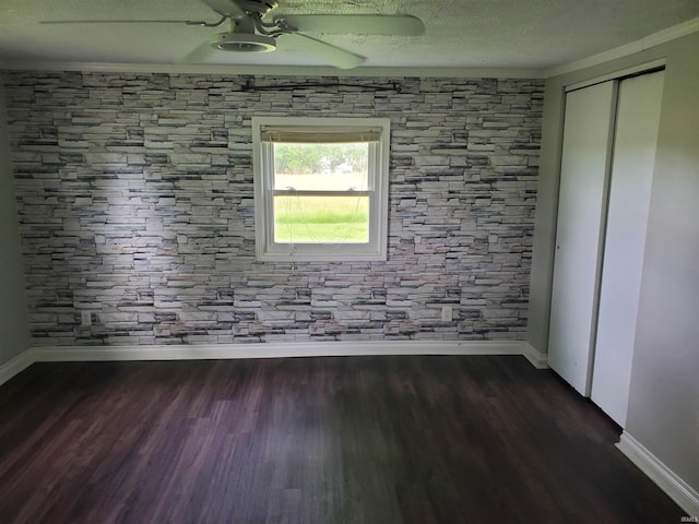 spare room featuring a textured ceiling, crown molding, ceiling fan, and dark wood-type flooring