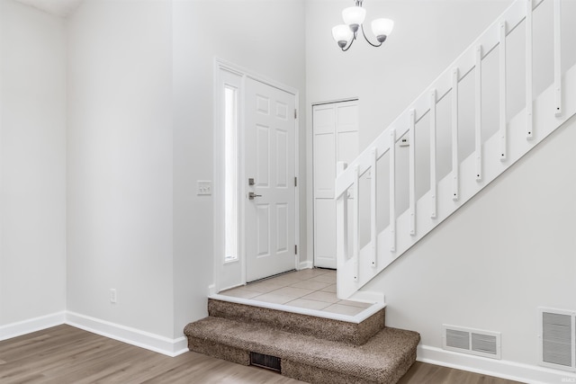 foyer entrance with light wood-type flooring and an inviting chandelier