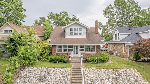 view of front of property with central AC and a front lawn