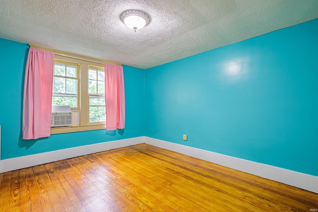 spare room with cooling unit, wood-type flooring, and a textured ceiling