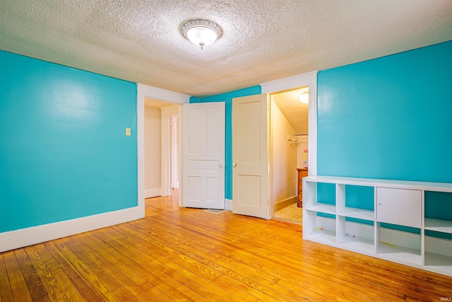 unfurnished bedroom featuring a closet, light hardwood / wood-style flooring, and a textured ceiling