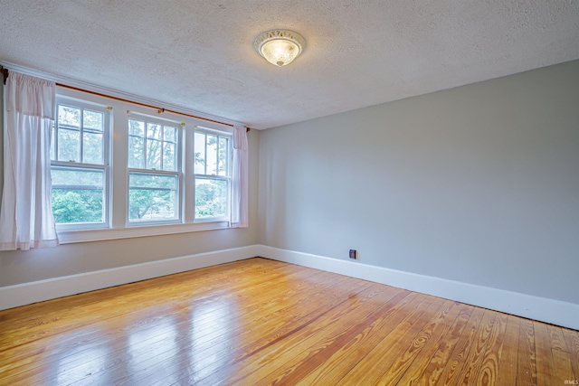 spare room with light wood-type flooring and a textured ceiling