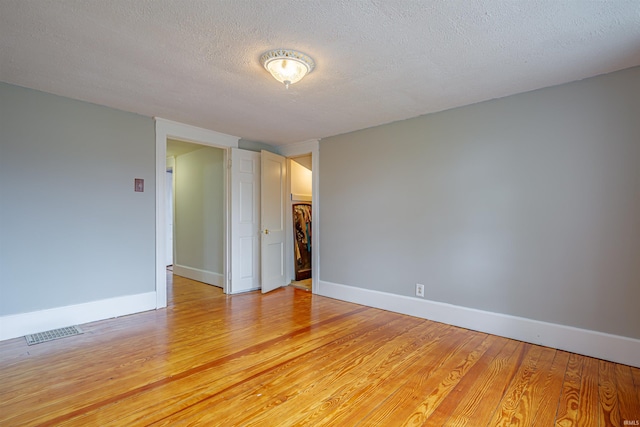 spare room with light wood-type flooring and a textured ceiling