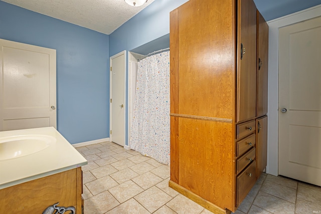 bathroom featuring tile patterned flooring, vanity, and a textured ceiling