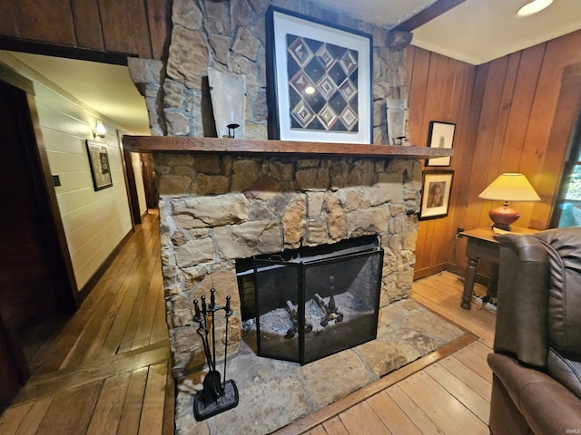 room details featuring hardwood / wood-style floors, wood walls, and a stone fireplace