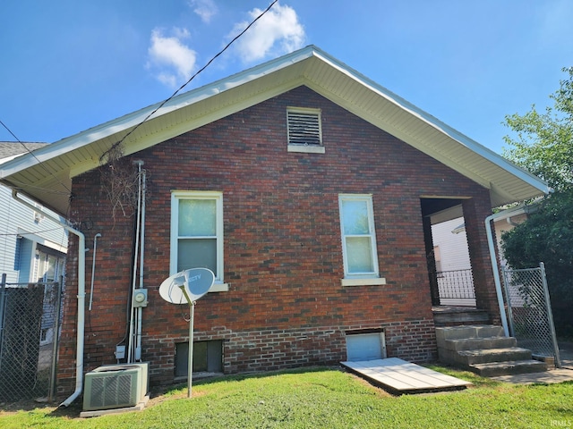 rear view of property featuring a lawn and central air condition unit