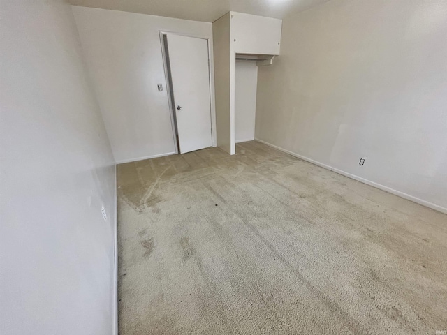 unfurnished bedroom featuring light carpet and a closet