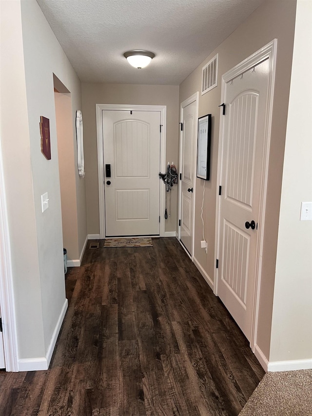 doorway to outside with dark wood-type flooring and a textured ceiling