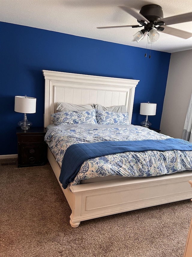 bedroom featuring a textured ceiling, dark carpet, and ceiling fan