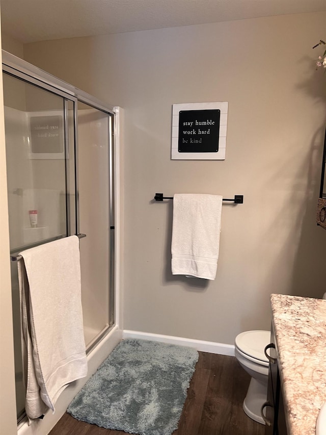 bathroom with hardwood / wood-style flooring, vanity, toilet, and an enclosed shower