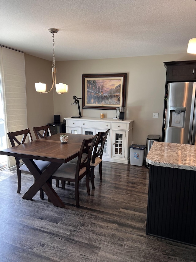 dining room featuring dark wood-type flooring, a textured ceiling, and a notable chandelier