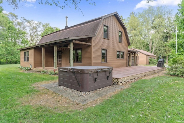 back of property with a yard, a wooden deck, and a hot tub