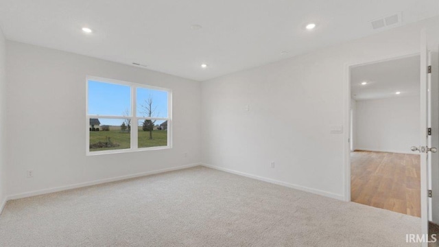 spare room featuring baseboards, recessed lighting, visible vents, and light colored carpet