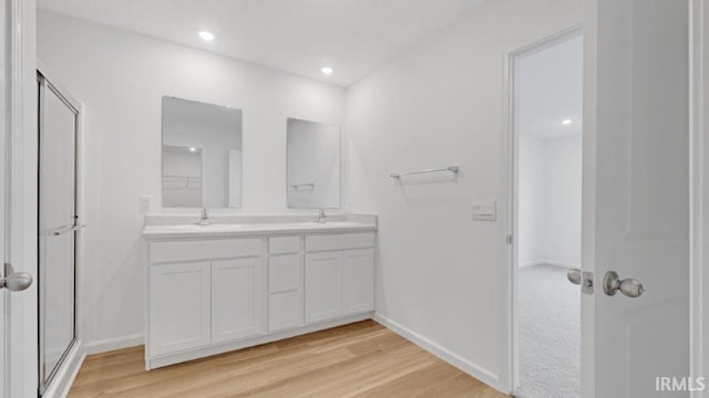 full bathroom featuring double vanity, baseboards, a sink, and wood finished floors