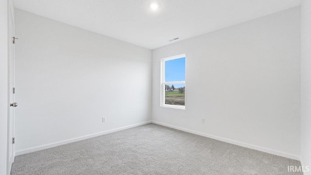 empty room with carpet, visible vents, and baseboards