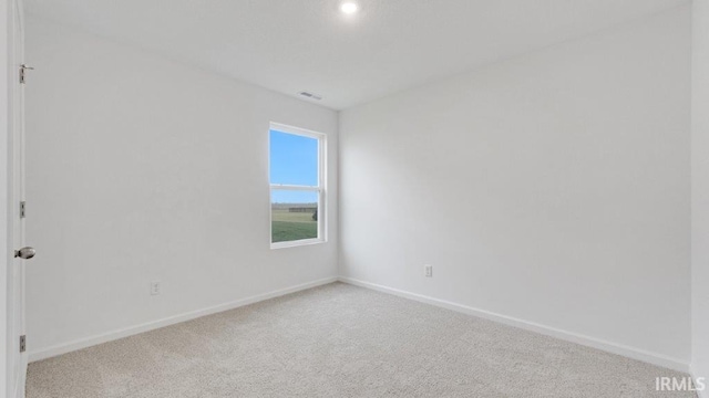 spare room featuring carpet flooring, visible vents, and baseboards