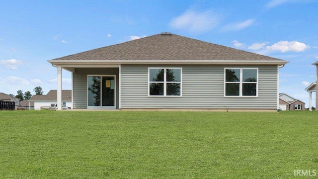 rear view of house featuring roof with shingles and a yard