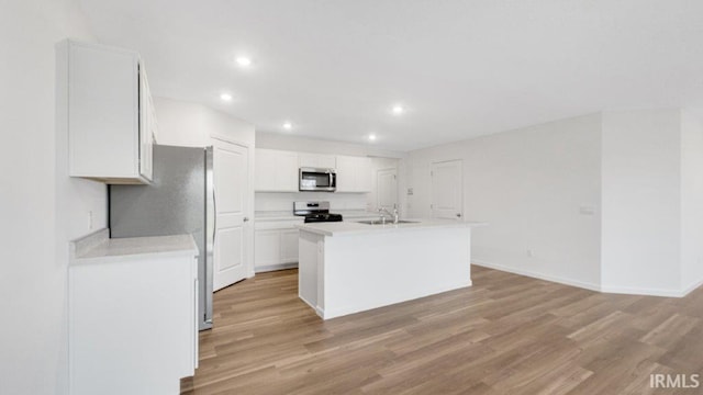 kitchen featuring stainless steel appliances, light countertops, a center island with sink, and white cabinetry