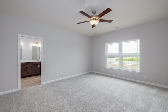 unfurnished bedroom featuring connected bathroom, ceiling fan, sink, and light carpet