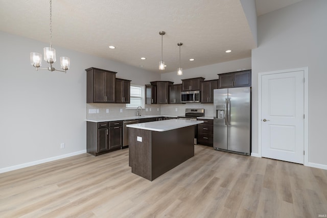 kitchen with a kitchen island, sink, stainless steel appliances, and hanging light fixtures