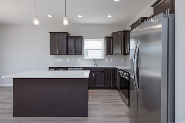 kitchen with hanging light fixtures, a kitchen island, stainless steel appliances, and sink