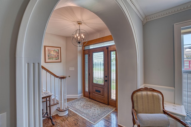 foyer entrance with hardwood / wood-style flooring, plenty of natural light, ornamental molding, and a notable chandelier