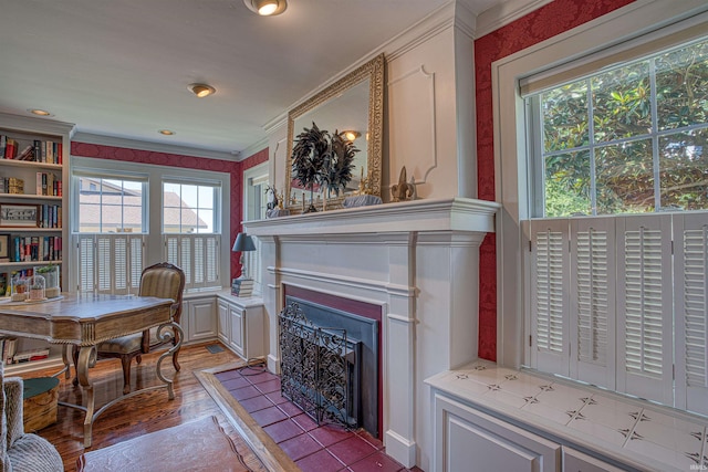 living room with ornamental molding, light wood-type flooring, a healthy amount of sunlight, and a tiled fireplace