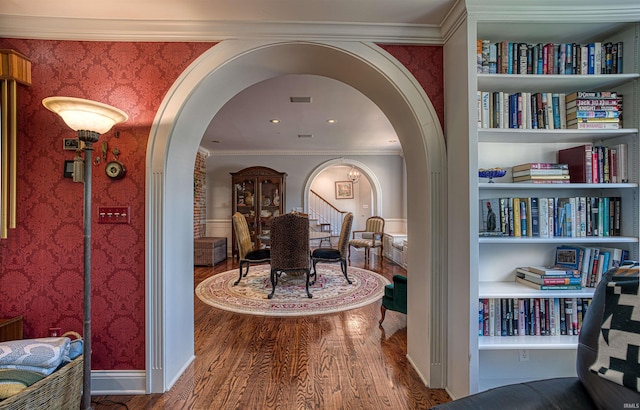 corridor featuring hardwood / wood-style floors, built in features, and ornamental molding