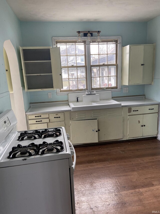 kitchen with dark wood-type flooring, sink, and white range with gas cooktop