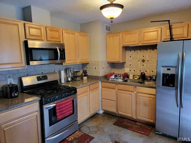 kitchen with decorative backsplash, appliances with stainless steel finishes, light brown cabinets, and sink