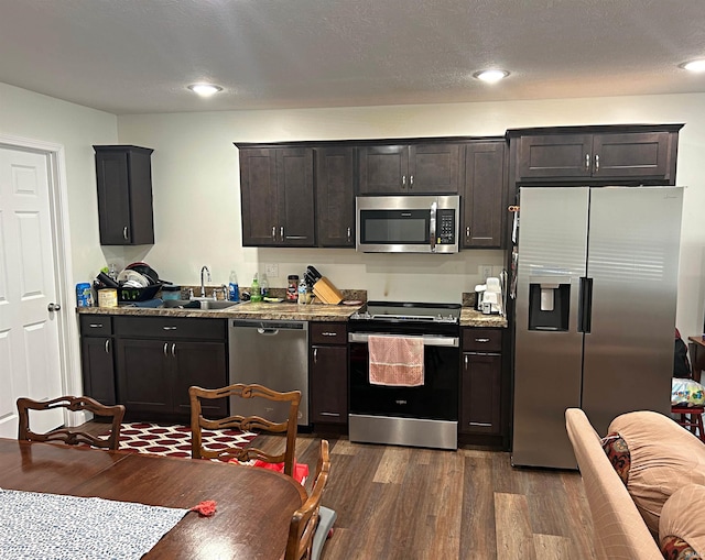 kitchen with stainless steel appliances, light stone counters, dark hardwood / wood-style floors, and sink