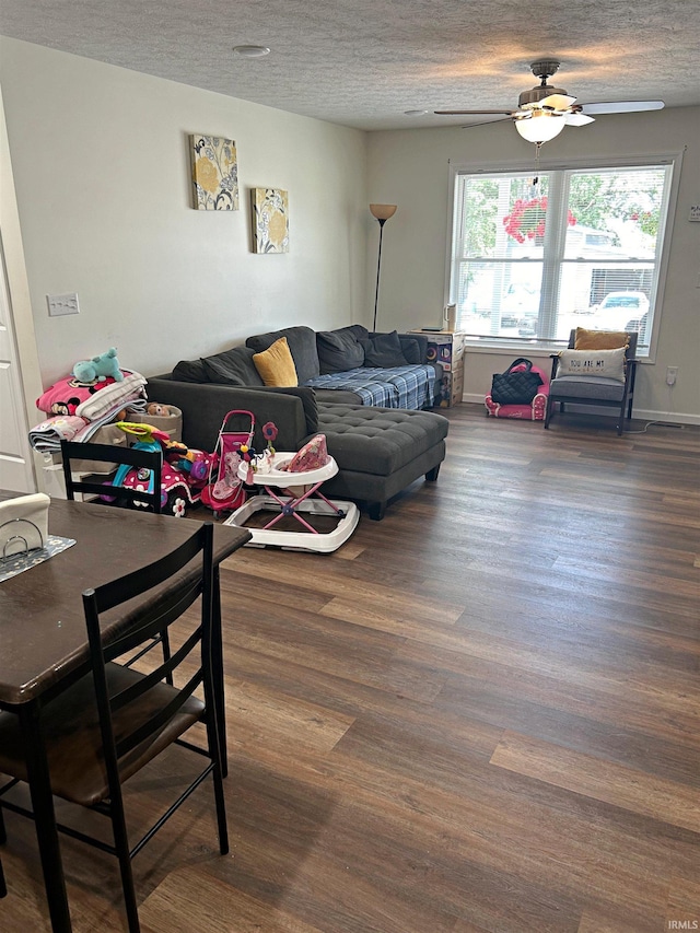 living room with a textured ceiling, ceiling fan, and dark hardwood / wood-style floors