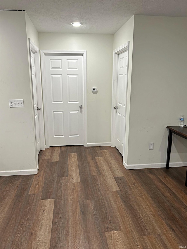 hall featuring a textured ceiling and dark wood-type flooring