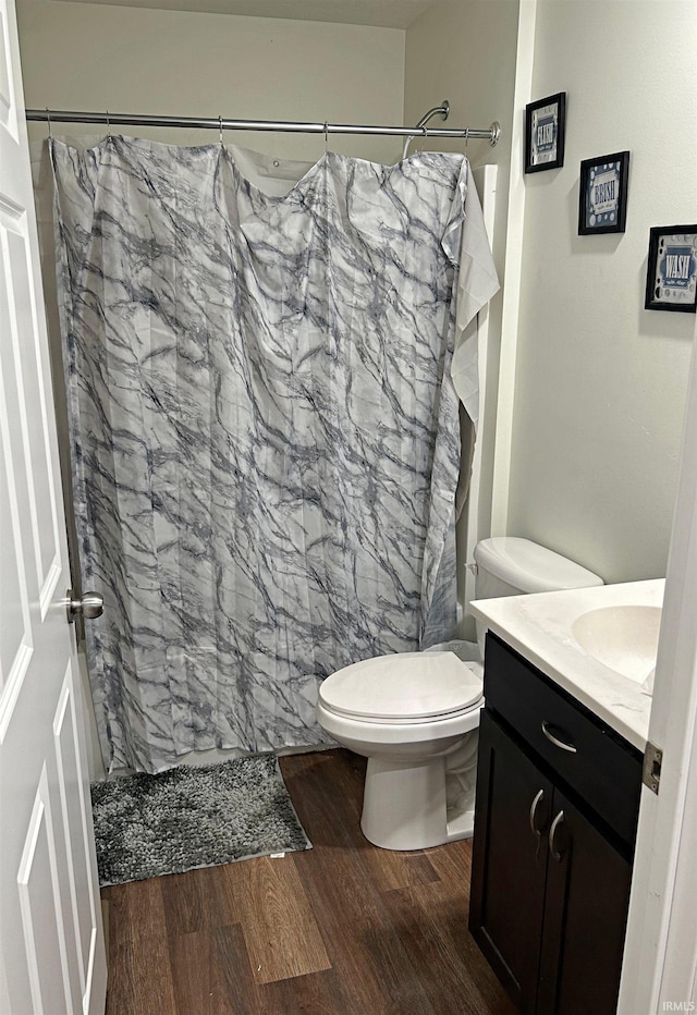 bathroom with a shower with shower curtain, hardwood / wood-style floors, vanity, and toilet