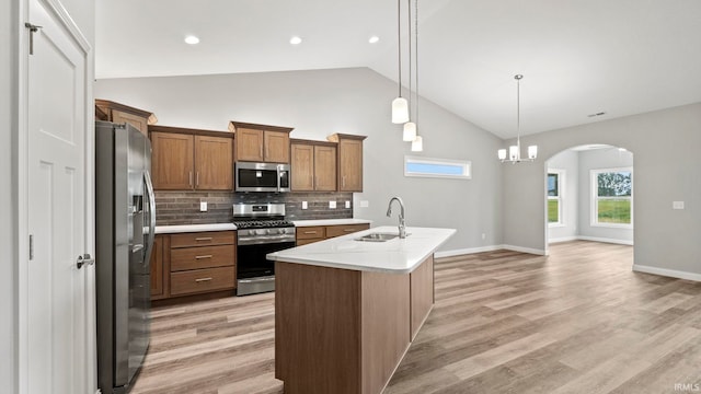 kitchen featuring sink, hanging light fixtures, decorative backsplash, an island with sink, and stainless steel appliances