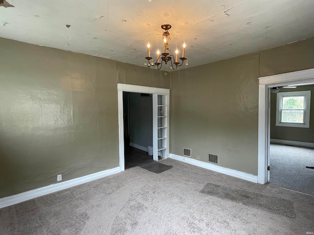 carpeted spare room featuring a notable chandelier