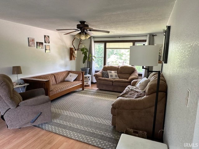 living room with a textured ceiling, wood-type flooring, and ceiling fan