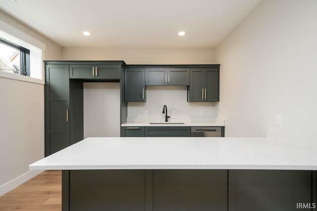 kitchen featuring kitchen peninsula, dishwasher, sink, and light hardwood / wood-style flooring