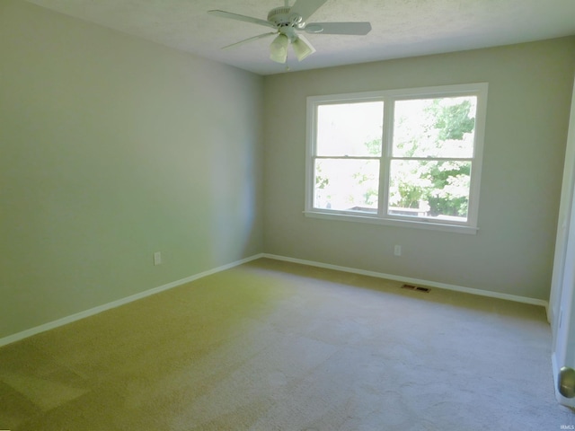 empty room with a textured ceiling, ceiling fan, and light carpet