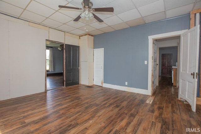 empty room featuring ceiling fan, a drop ceiling, and dark wood-type flooring