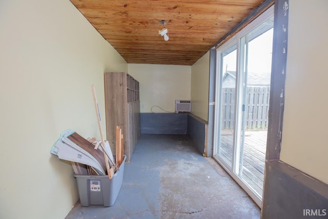 hall featuring a wall mounted AC, concrete floors, and wood ceiling