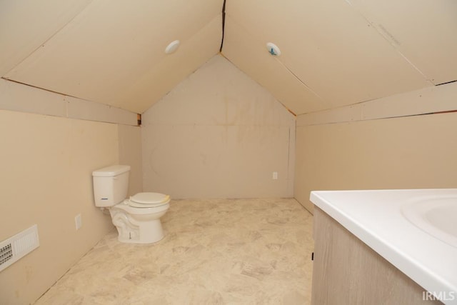 bathroom featuring vanity, toilet, and vaulted ceiling