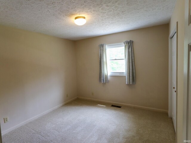 carpeted spare room featuring a textured ceiling