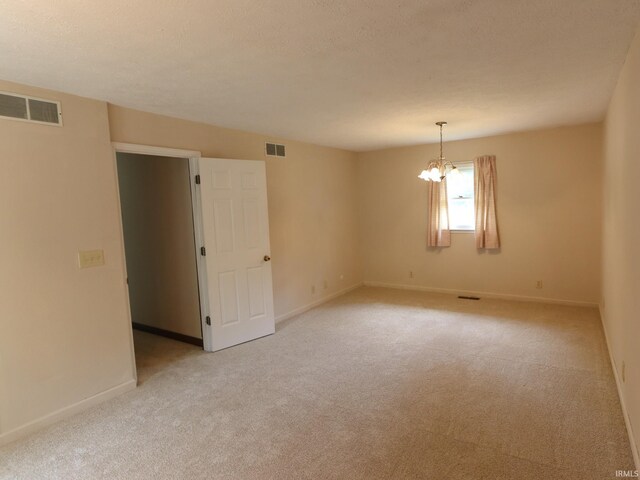 unfurnished room with light carpet and an inviting chandelier