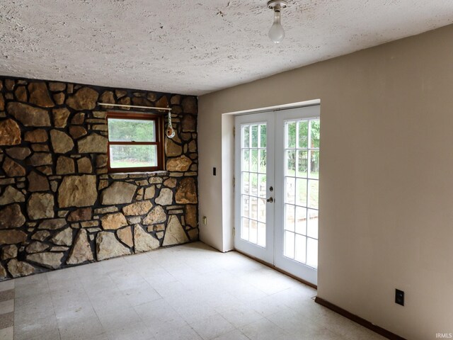 empty room with french doors and a textured ceiling