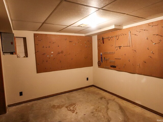 spare room featuring a paneled ceiling, concrete flooring, and a workshop area